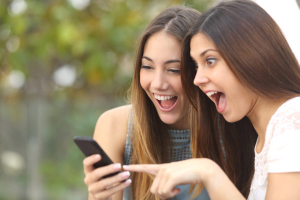 Zwei Frauen schauen auf eine Smartphone und freuen sich